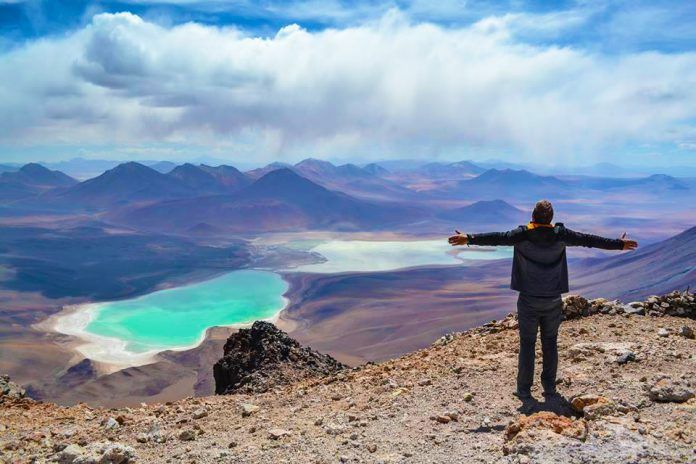 Viajero frente a paisaje desértico y laguna turquesa