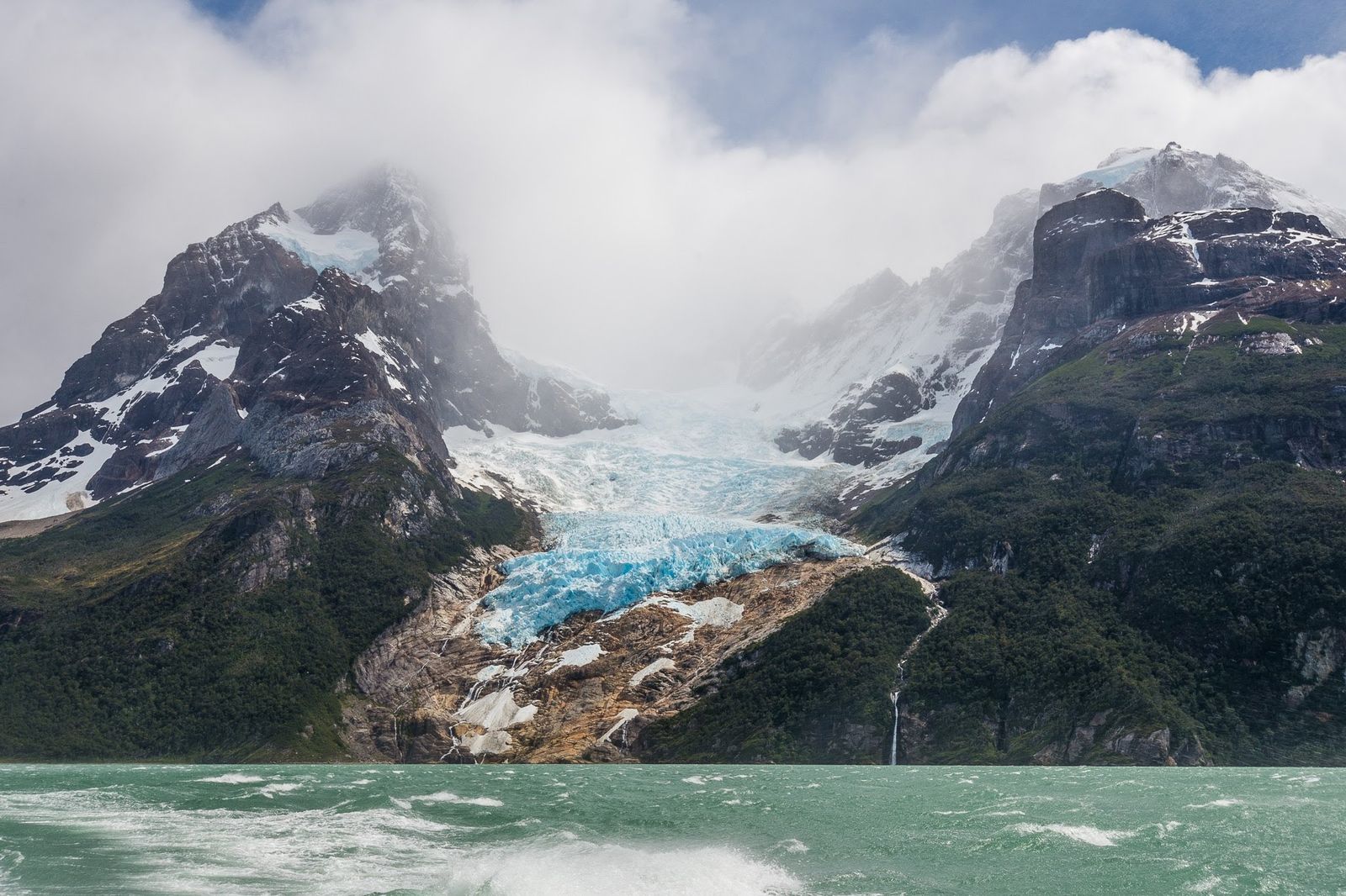 Glaciar entre montañas y frente a lago