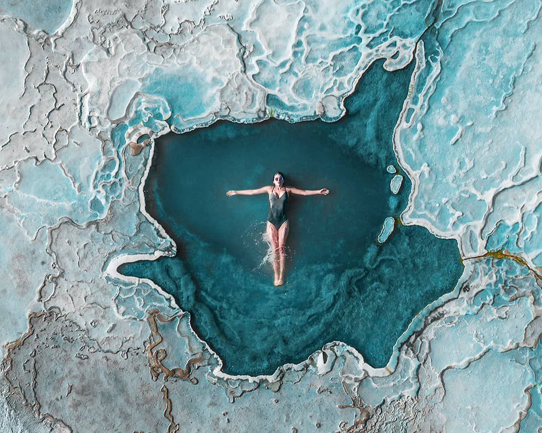 Mujer bañandose en una laguna color turquesa